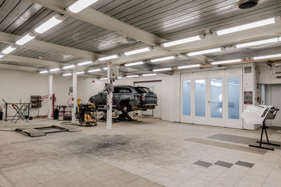 Interior view of a modern car repair garage with vehicle on lift and equipment.