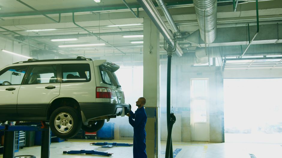 Mechanic conducts vehicle inspection in an automotive garage setting.