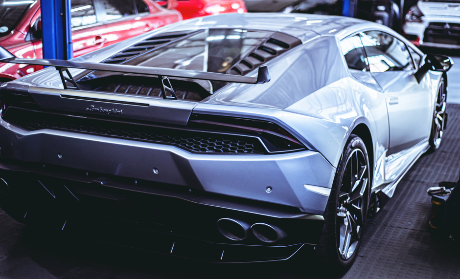 A stunning silver Lamborghini Huracan showcasing its powerful rear and spoiler in a garage setting.