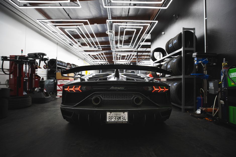 Rear view of Lamborghini Aventador in a sleek modern garage with LED lighting.