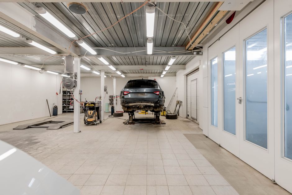 Well-lit garage with a car on a hydraulic lift ready for repair.